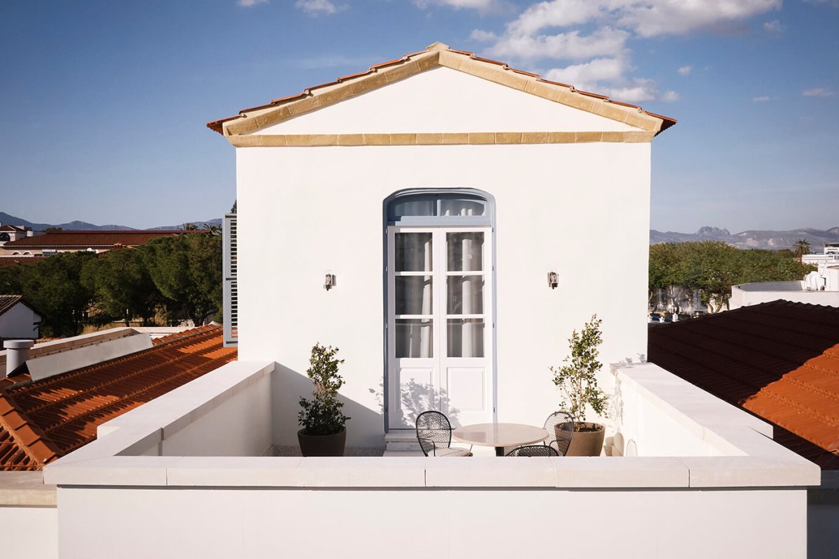A whitewashed rooftop terrace at Amyth of Nicosia above terracotta roofs, with the mountains beyond