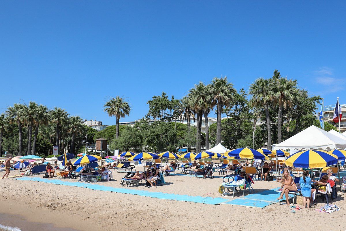 Bijou Plage near Pointe Croisette with blue beach mats laid over the sand, parasols and palm trees
