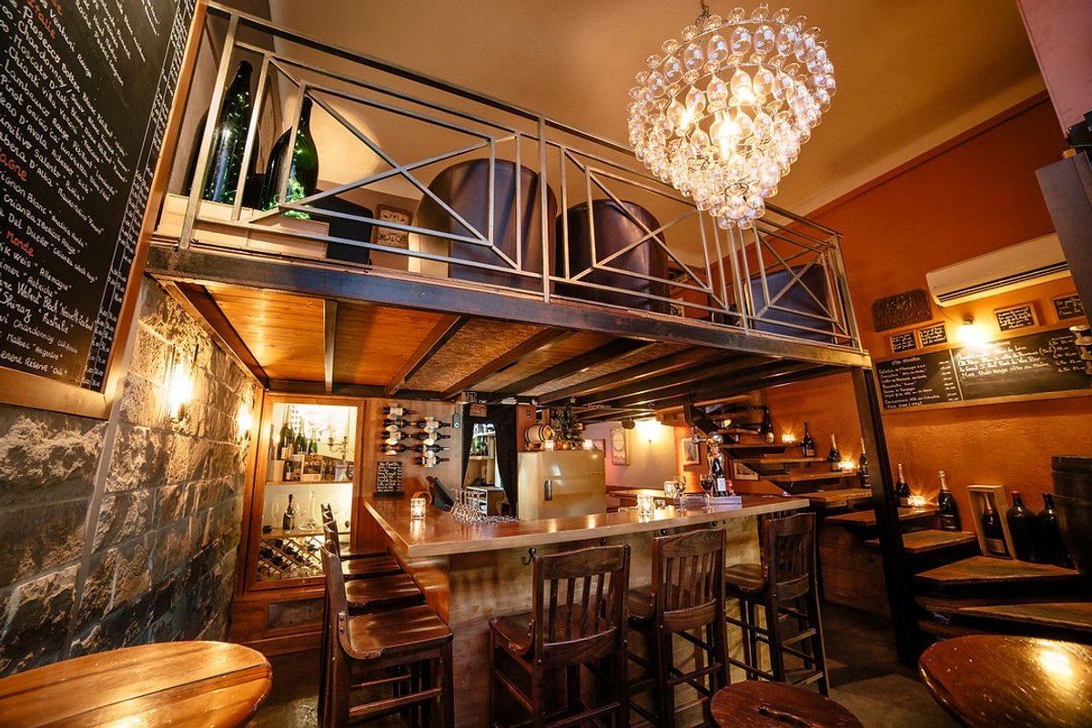 The warm-lit wooden bar and mezzanine of Le Bar à Vin on rue Marceau in Cannes