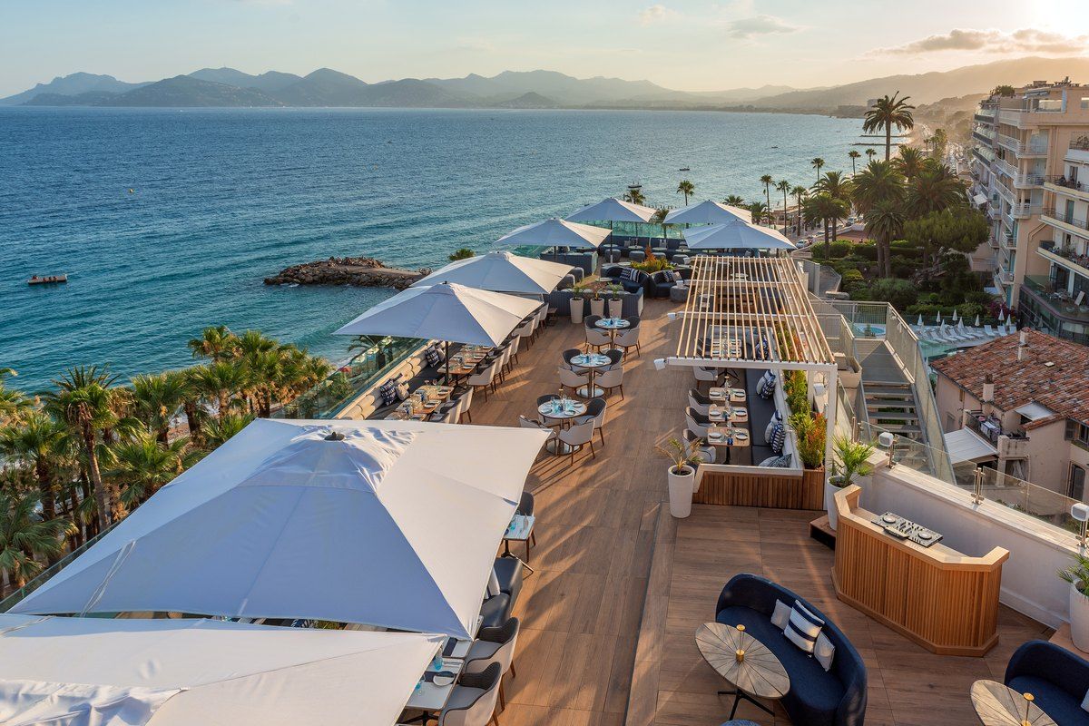 The Marea rooftop on the Canopy by Hilton in Cannes, with parasols, sea and the hills beyond in evening light