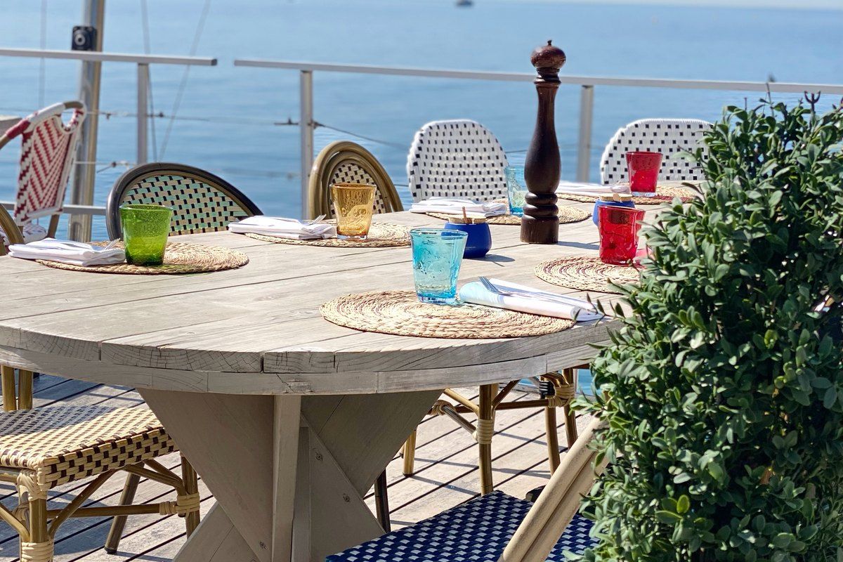 A laid table with coloured glasses on the sea-view terrace of Atrego, on the rocks at the port of Cap-d'Ail