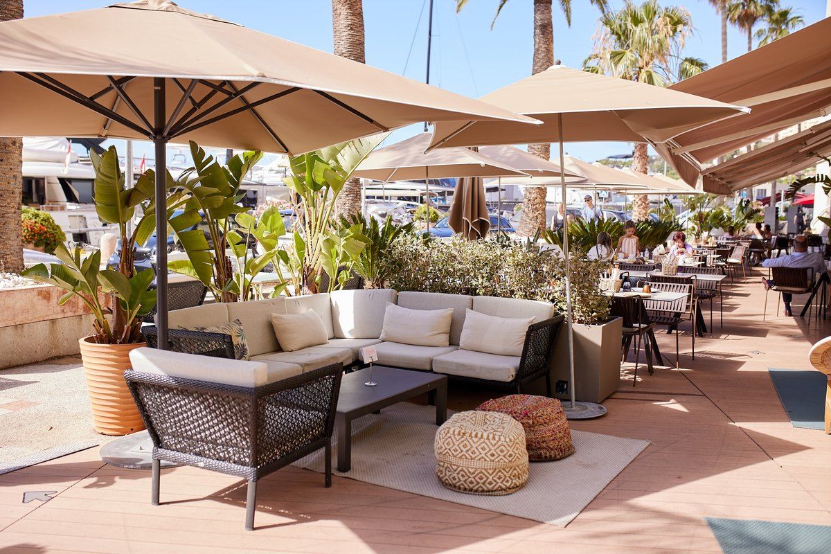 Lounge sofas, rattan poufs and parasols on the port-side terrace of the Bolinas bar in Cap-d'Ail