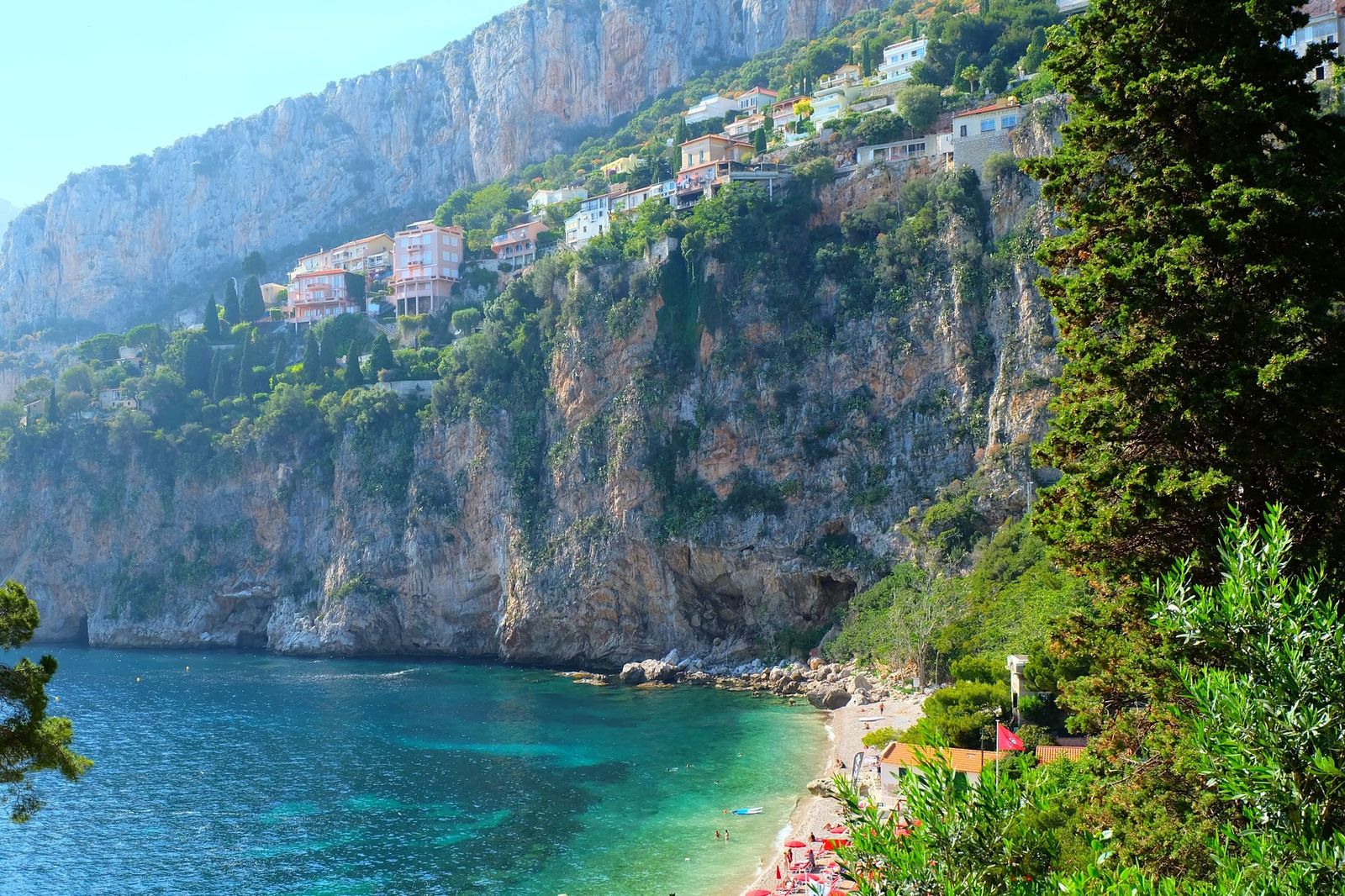 Plage Mala at Cap d'Ail seen through the trees, with the cliffs rising behind