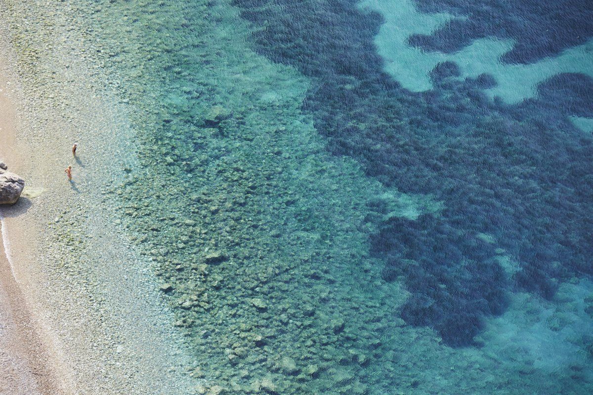 Looking down on the fine pebbles and clear turquoise shallows of Plage Mala in Cap-d'Ail
