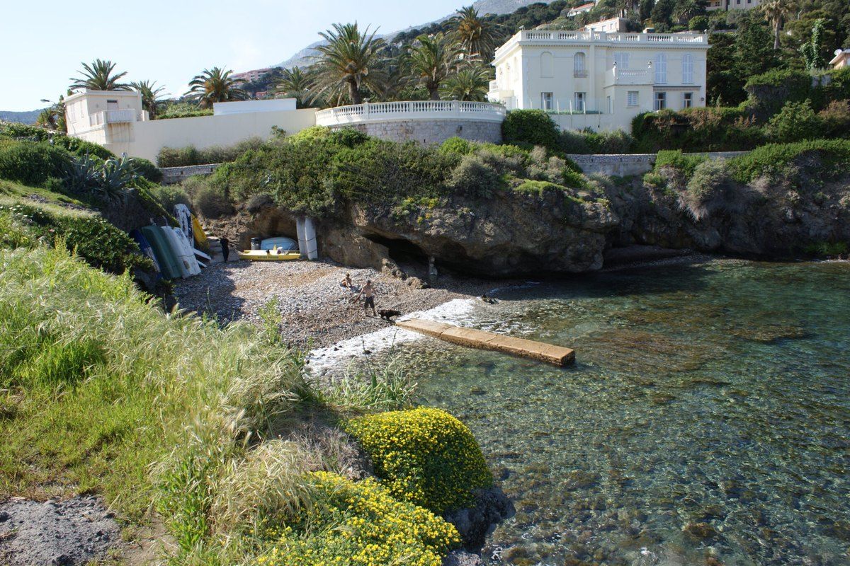 The little beach and clear water at the Pointe des Douaniers in Cap-d'Ail, below a white Belle Époque villa