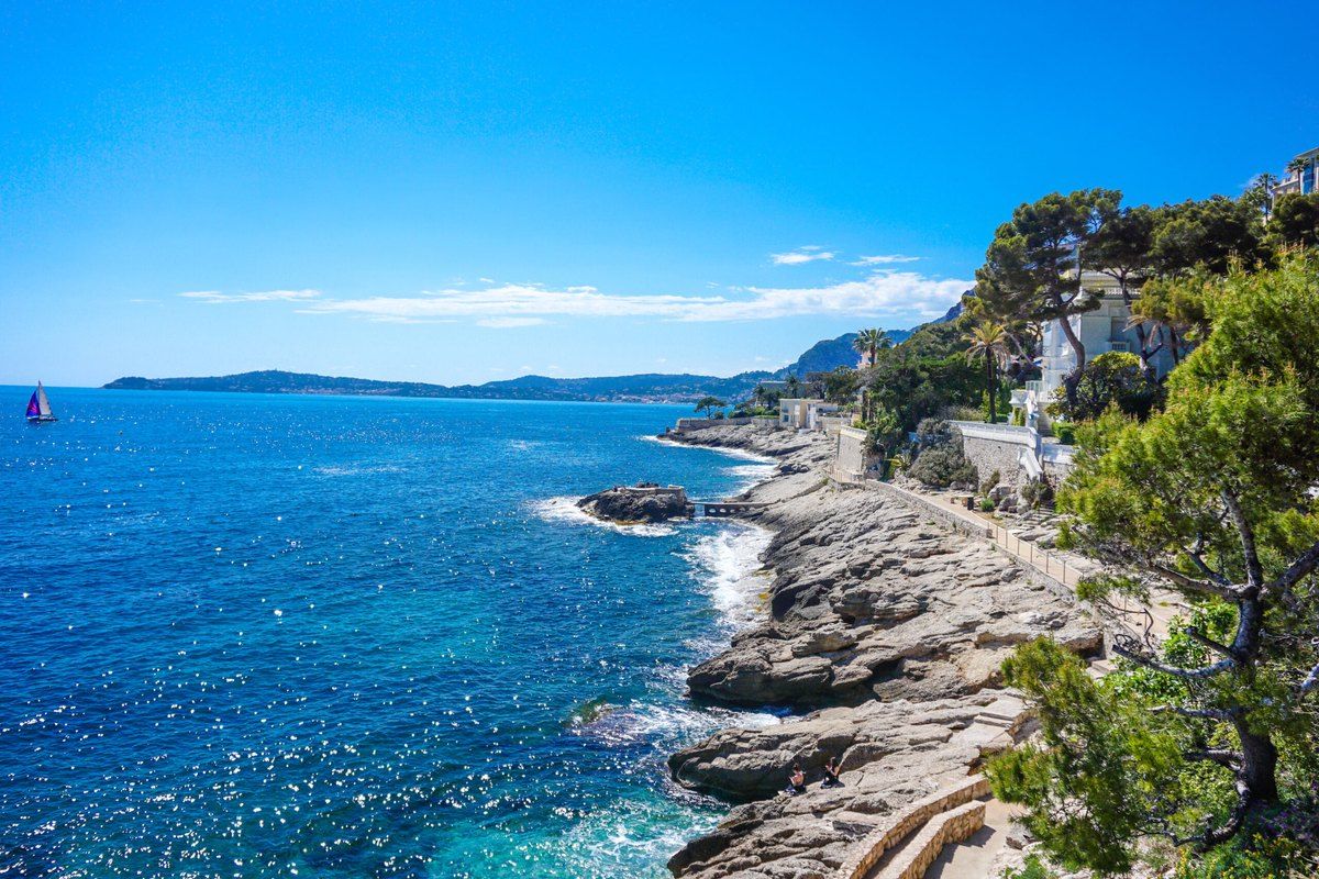 The coastal path of Cap-d'Ail running along pale rocks and deep blue water towards the next headland