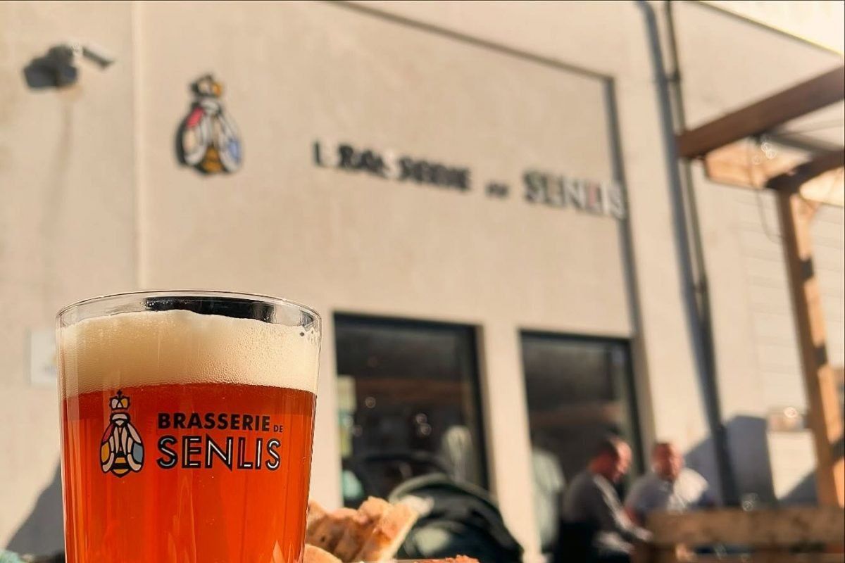 A glass of Brasserie de Senlis beer in front of the brewery