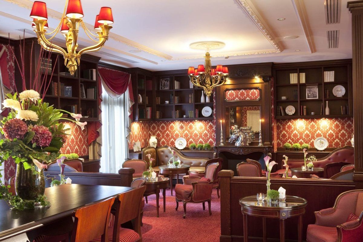 Red lamps, bookcases and velvet armchairs in the Lounge Bar of the Auberge du Jeu de Paume