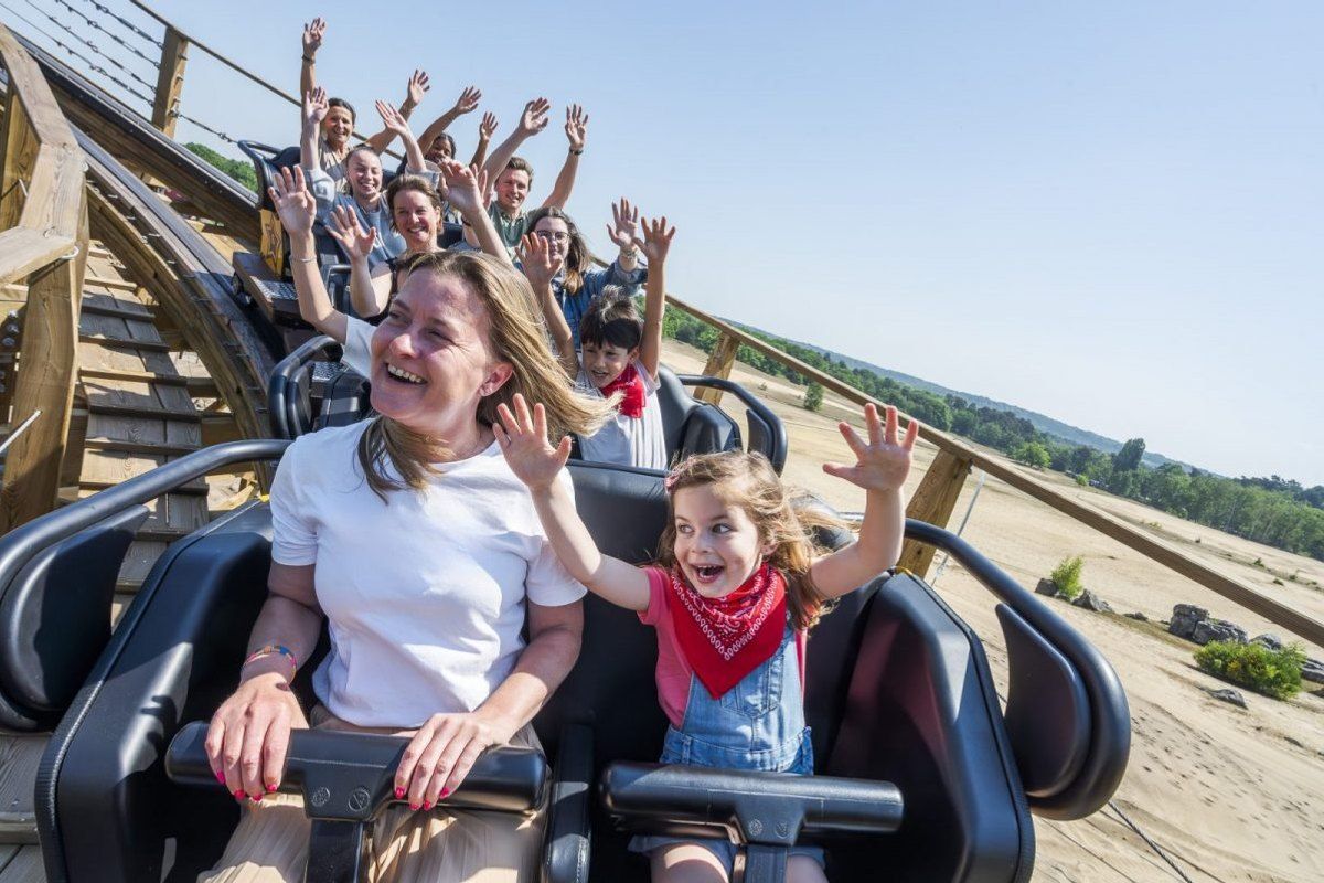 A mother and daughter with arms raised on a roller coaster at La Mer de Sable