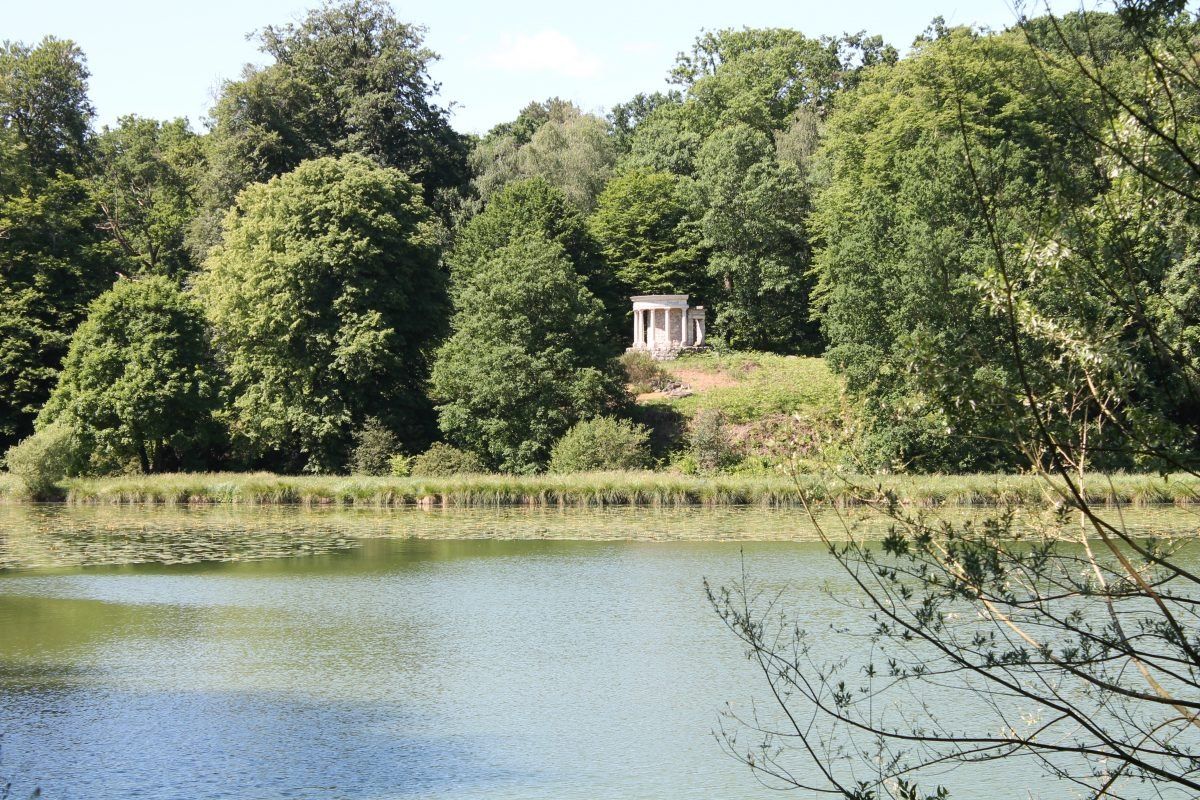 A lake below wooded slopes and a small temple in the Parc Jean-Jacques Rousseau at Ermenonville