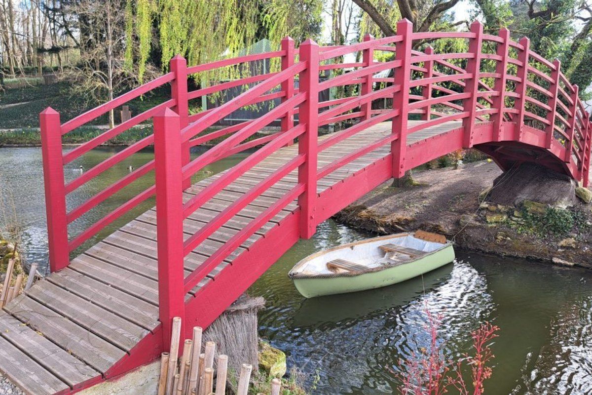 A red Japanese bridge over the pond at the Potager des Princes