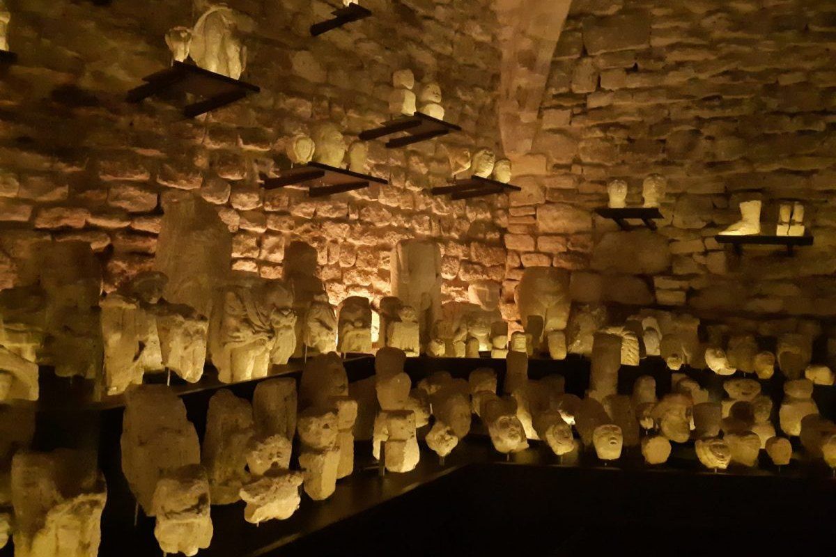 Rows of carved stone ex-votos lit in the vaulted cellar of the Musée d'Art et d'Archéologie in Senlis