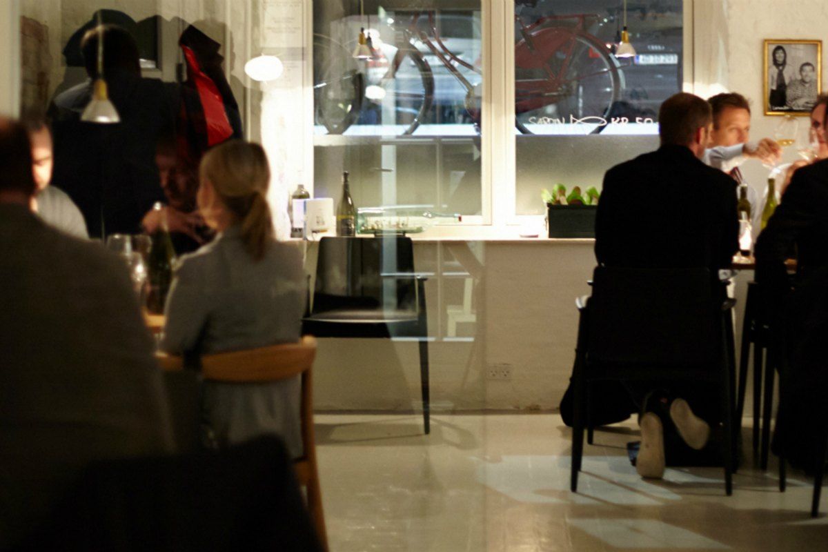 Guests at candlelit tables inside Den Vandrette wine bar on Havnegade in the evening