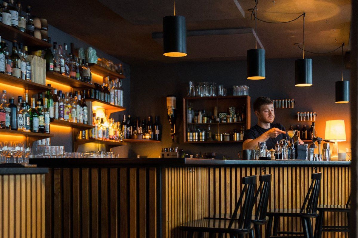The wood-panelled basement bar at Duck and Cover in Vesterbro, with pendant lamps and shelves of bottles