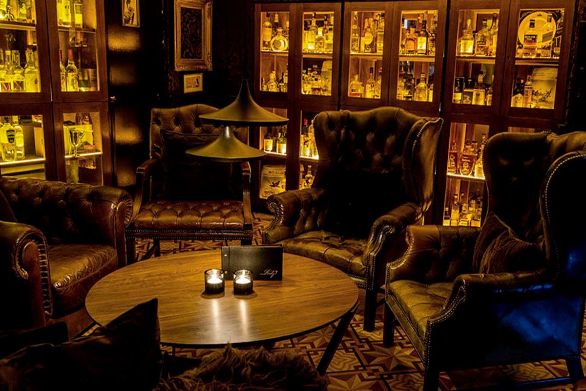 Leather armchairs, candlelight and back-lit bottle cabinets in the lounge at Ruby cocktail bar on Nybrogade