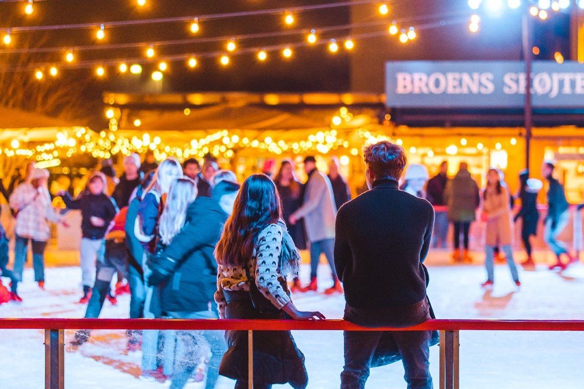 Skaters under strings of lights at Broens ice rink by the Inner Harbour Bridge in the evening