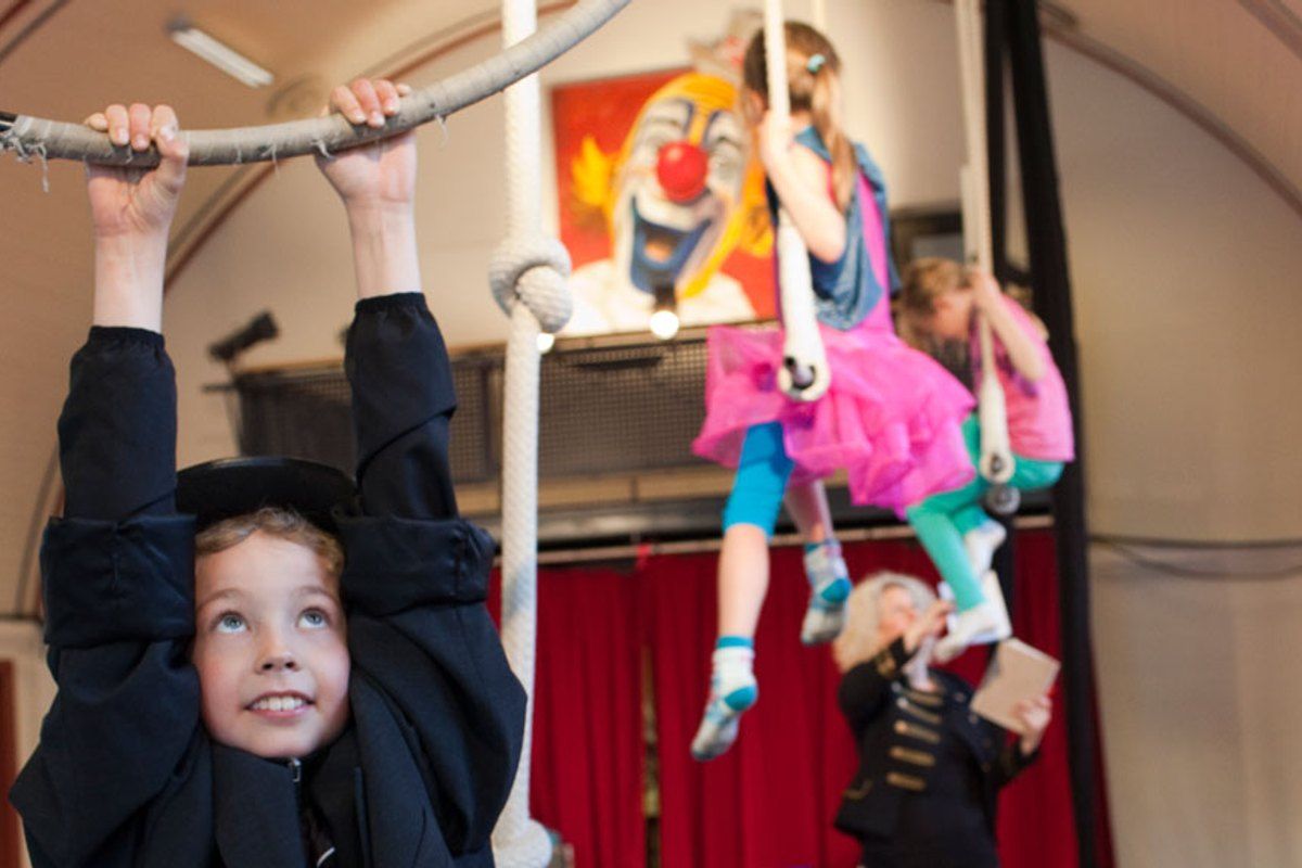 Children trying the trapeze and hanging bars at a circus workshop in the Circus Museum in Hvidovre