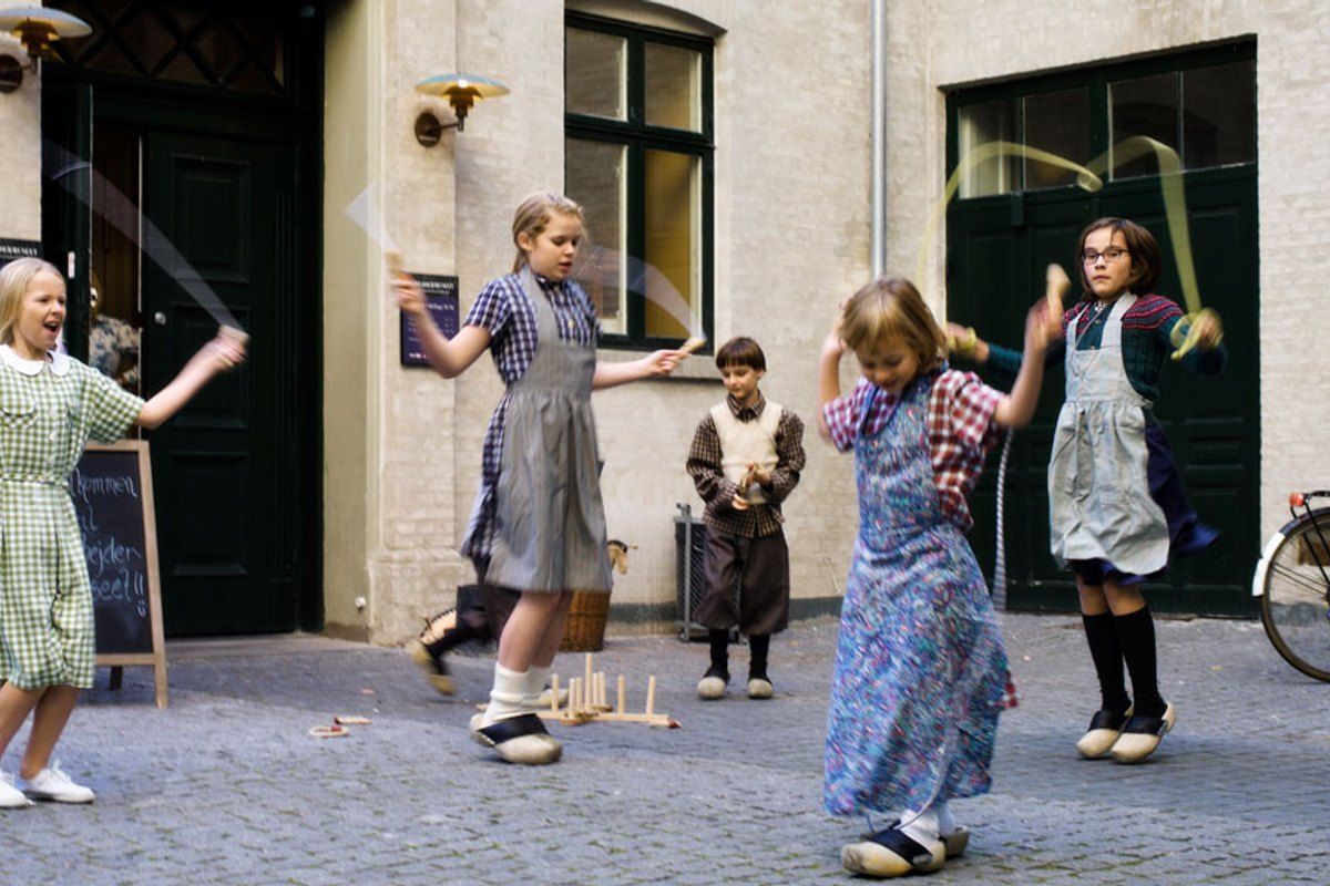Children in old-fashioned aprons and clogs playing in the backyard of the children's museum at Arbejdermuseet