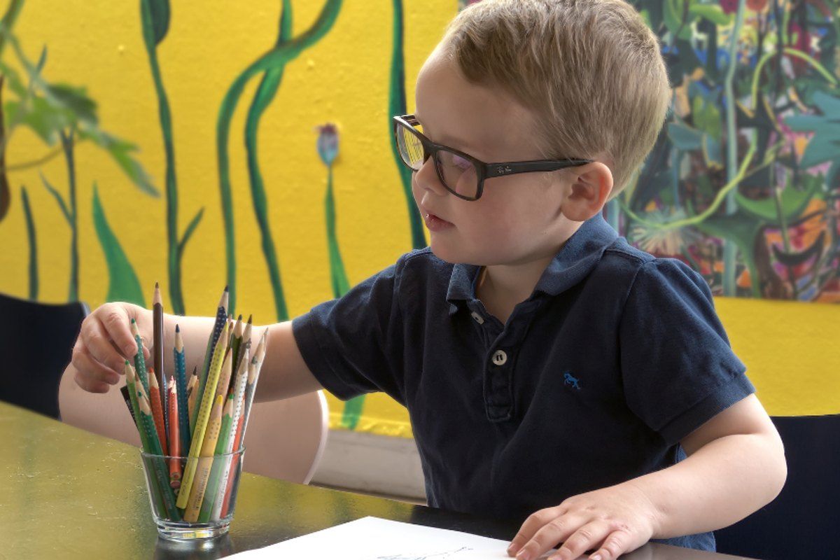 A boy choosing coloured pencils at a table in the Children's House at Louisiana Museum of Modern Art
