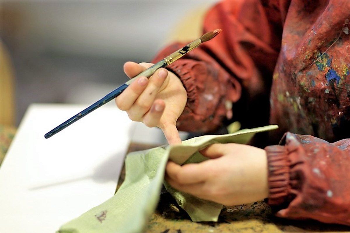 A child's paint-stained hands holding a brush in the Children's Workshop at SMK, the National Gallery of Denmark