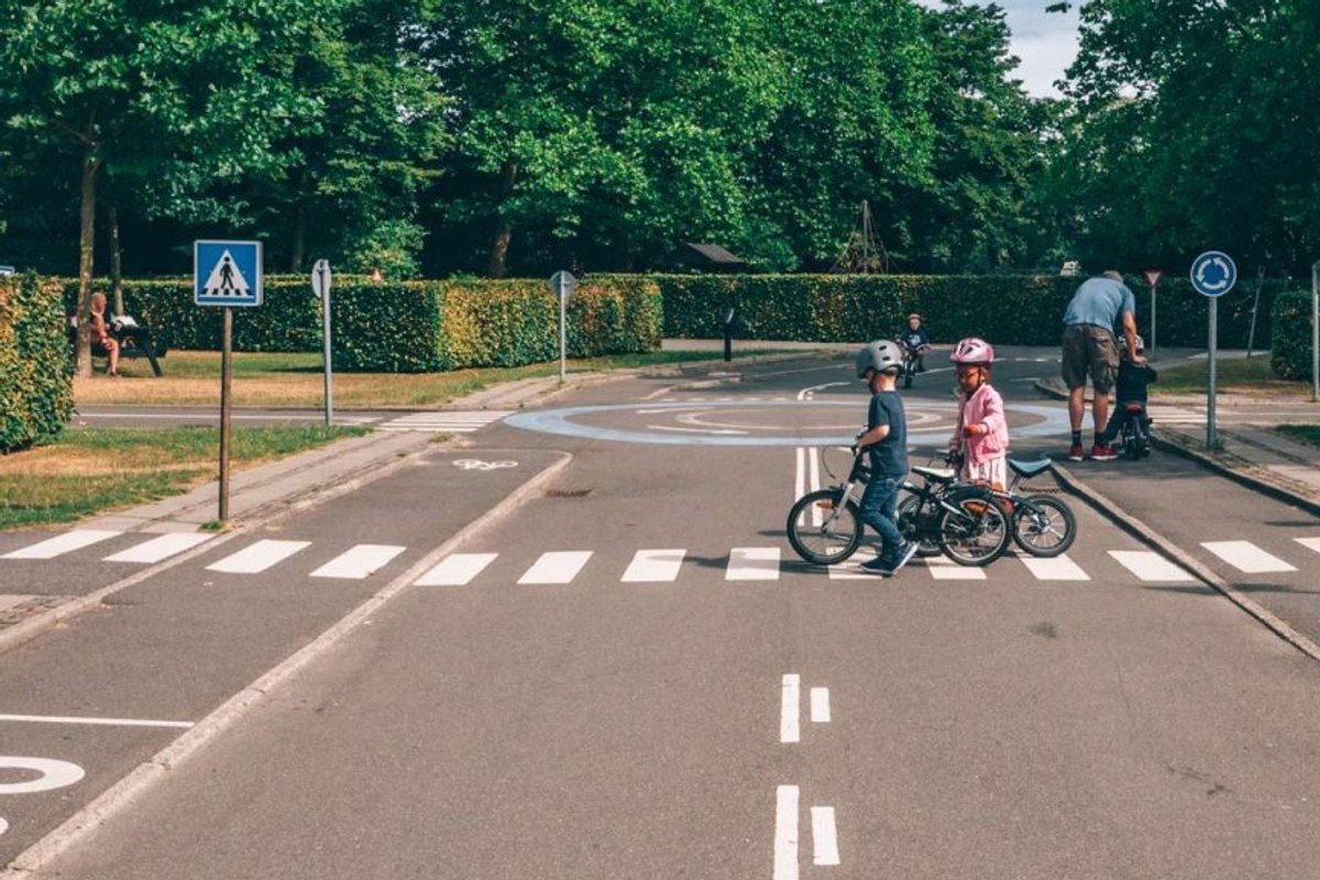 Children on bicycles at a zebra crossing with road signs on the Children's Traffic Playground in Fælledparken