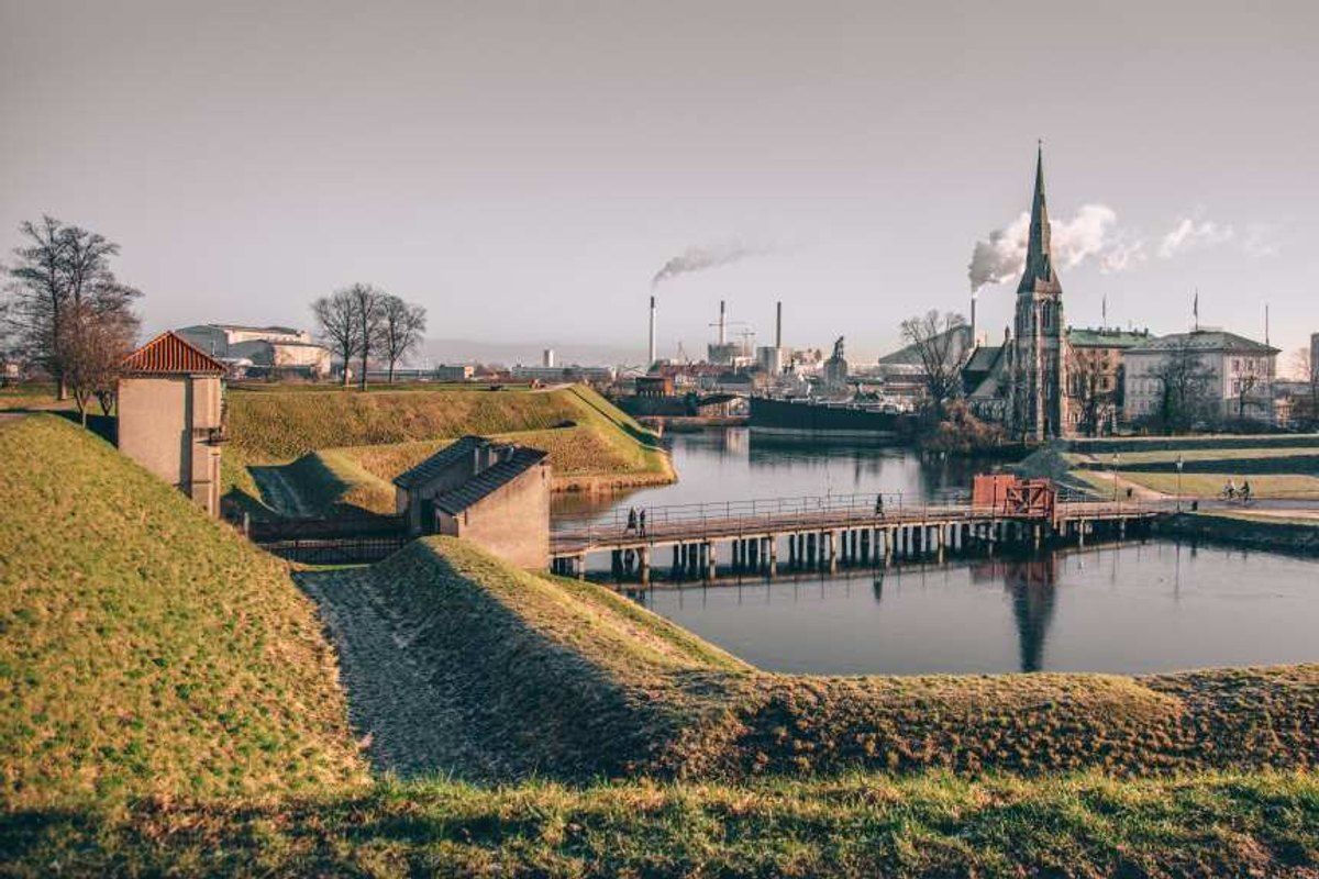 The grassy ramparts and moat of Kastellet, the Citadel, with the spire of St Alban's Church beyond