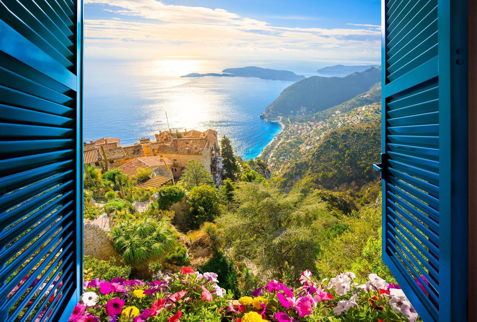 An open window with blue shutters and flowers looking down to the coast from Èze