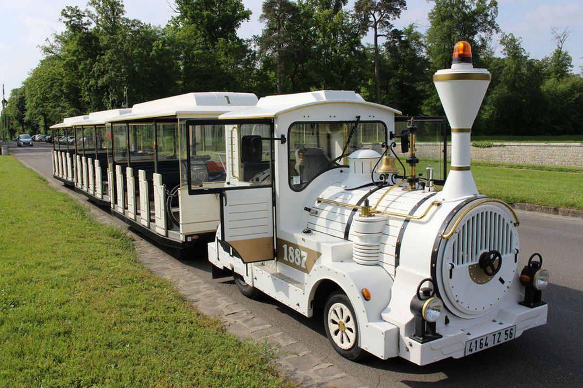 The white little tourist train of the Château de Fontainebleau parked on an avenue in the park