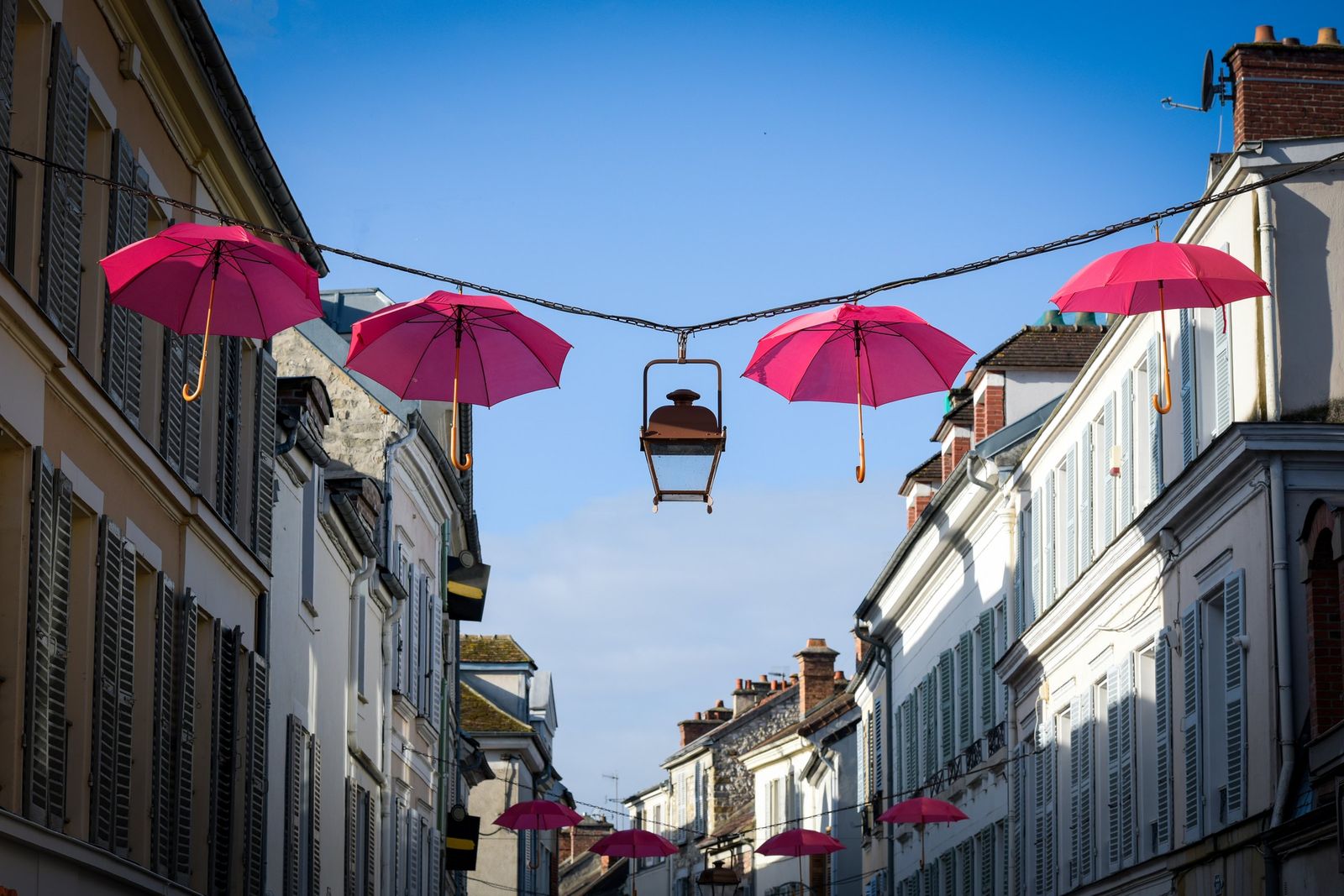 Pink umbrellas strung above a street in Fontainebleau for Pink October