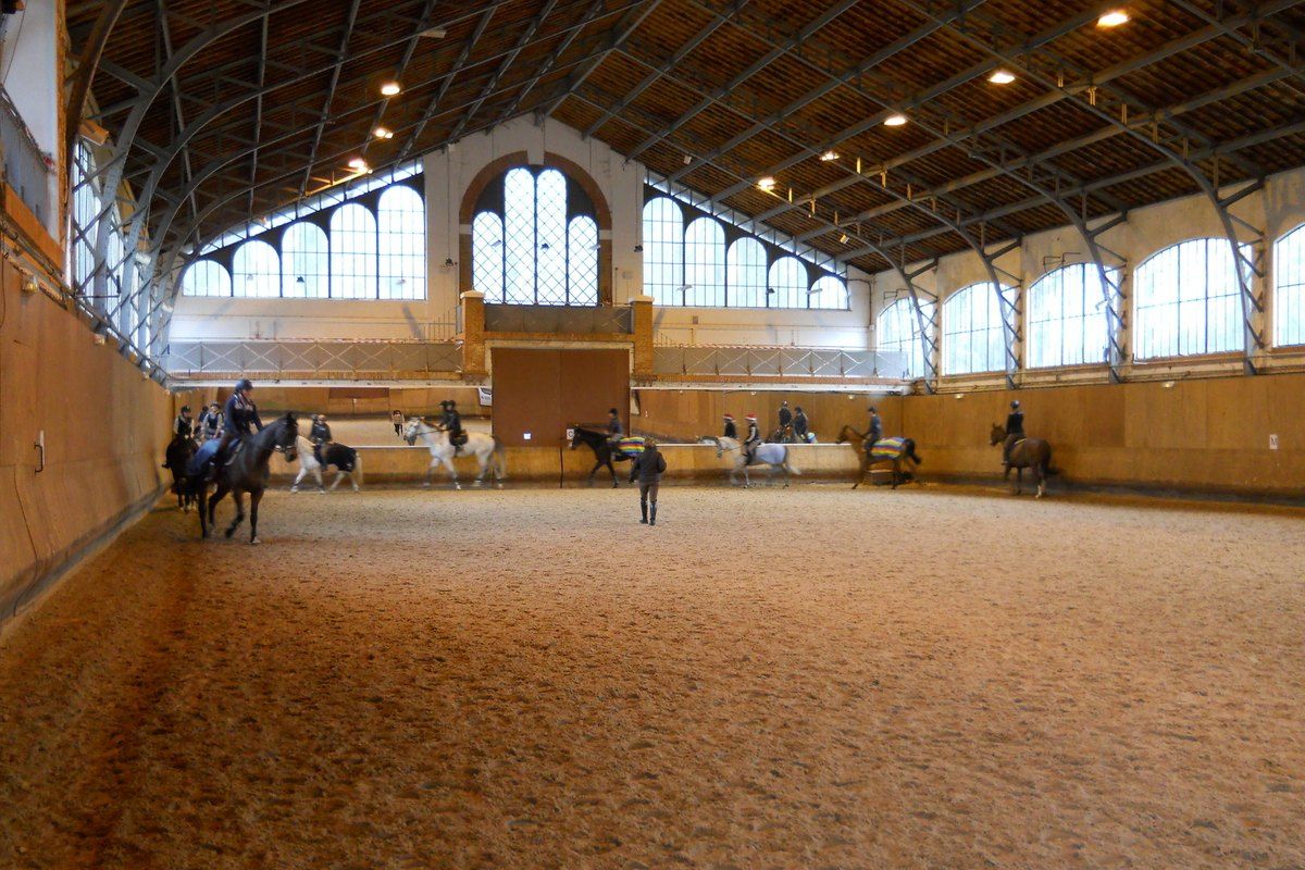 Riders in the covered riding hall of the Société Équestre de Fontainebleau
