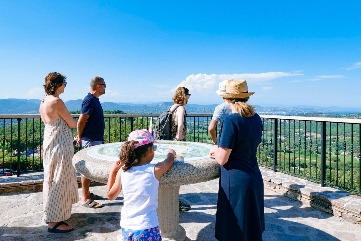 A family at the orientation table on the village terrace of Gassin, looking out over the gulf