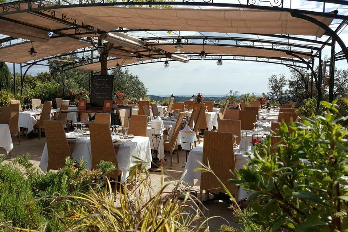 Tables under the shaded terrace of Le Pescadou with a view over the countryside below Gassin
