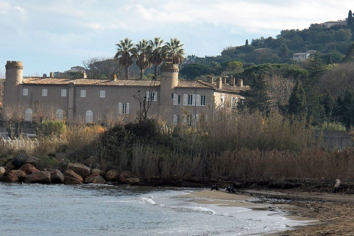 The Château Bertaud behind reeds and the sandy Plage de Bertaud at the Marines de Gassin