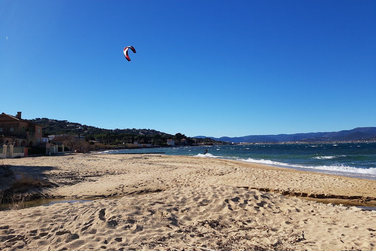 The wide sandy Plage de la Bouillabaisse at Gassin, with a kitesurfer over the gulf