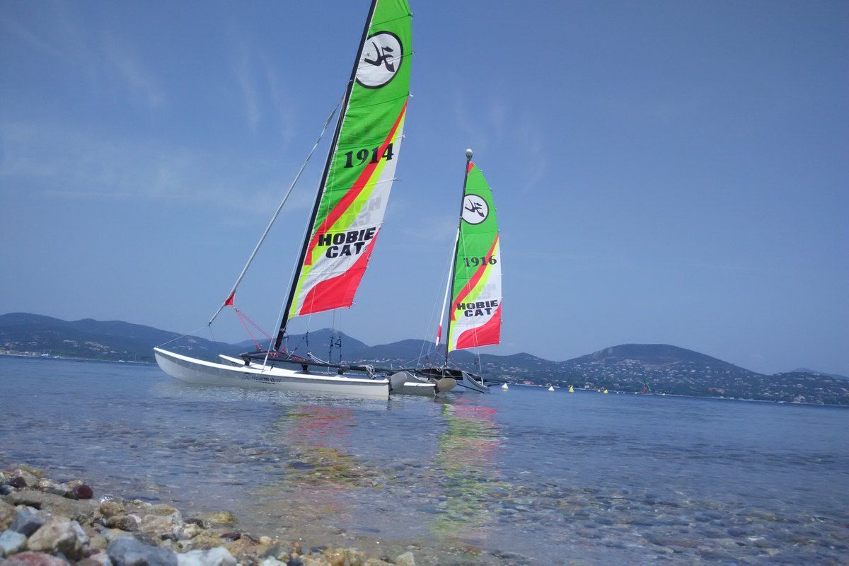 Two beach catamarans with bright sails at the sailing school on the Plage de la Moune, Gassin