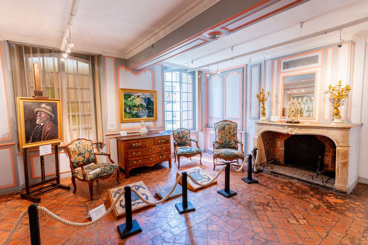 A period room with paintings, armchairs and a marble fireplace in the Musée Nicolas Poussin, Les Andelys