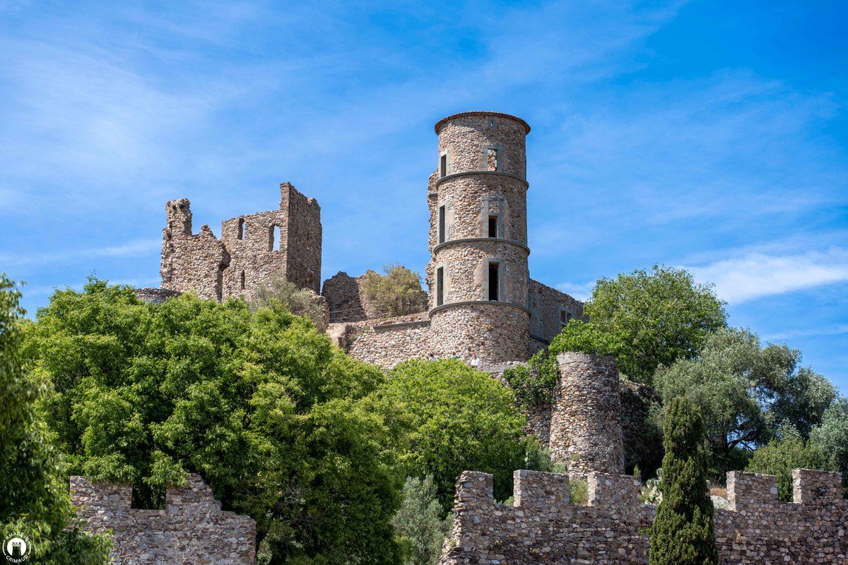 The ruined towers of the Château de Grimaud above crenellated walls and olive trees