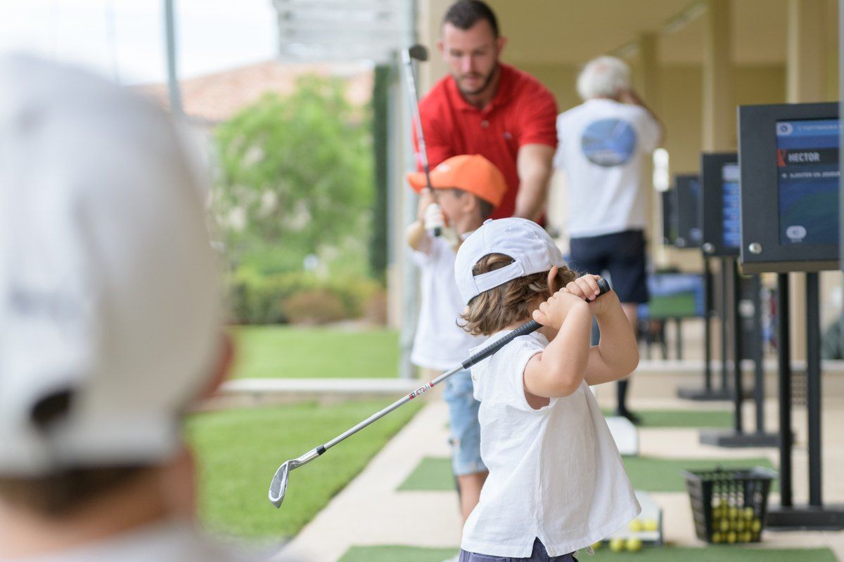 Children learning to swing a golf club with a coach on the driving range at Golf Up, Grimaud