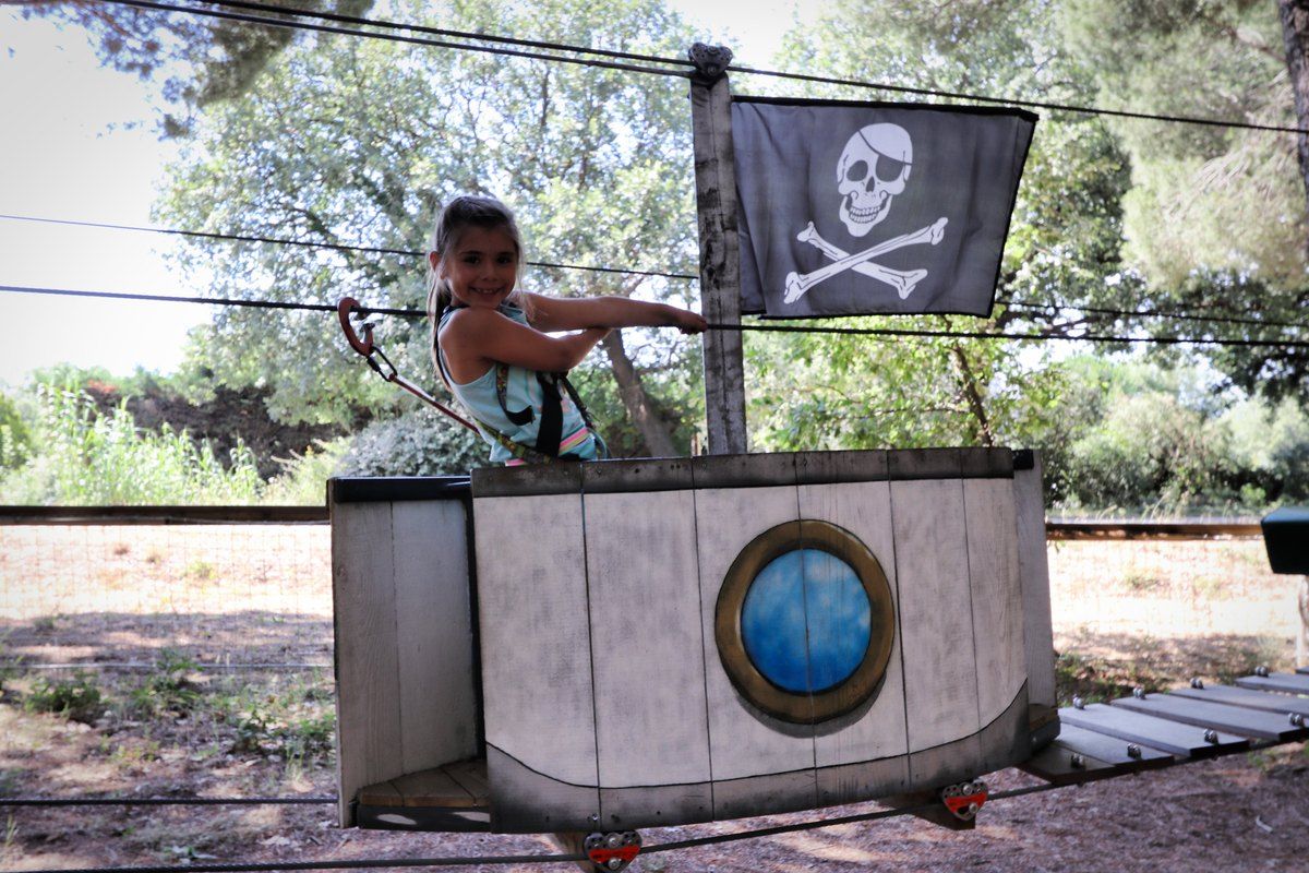 A child on a zip line beside a pirate flag on one of the courses at Grimaud Aventure