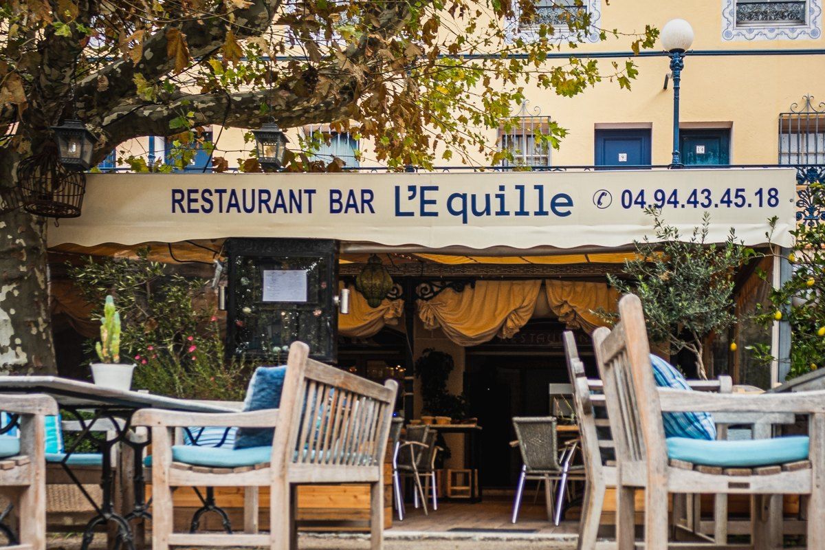 Teak chairs on the terrace of L'Équille under its awning on place François Spoerry, Port Grimaud