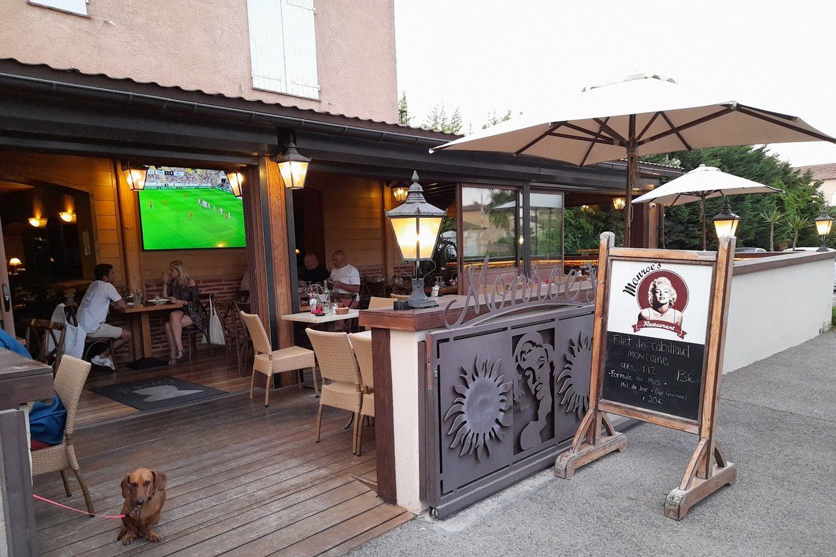 The covered terrace of Monroe's Pub in Port Grimaud with a football match on the screen