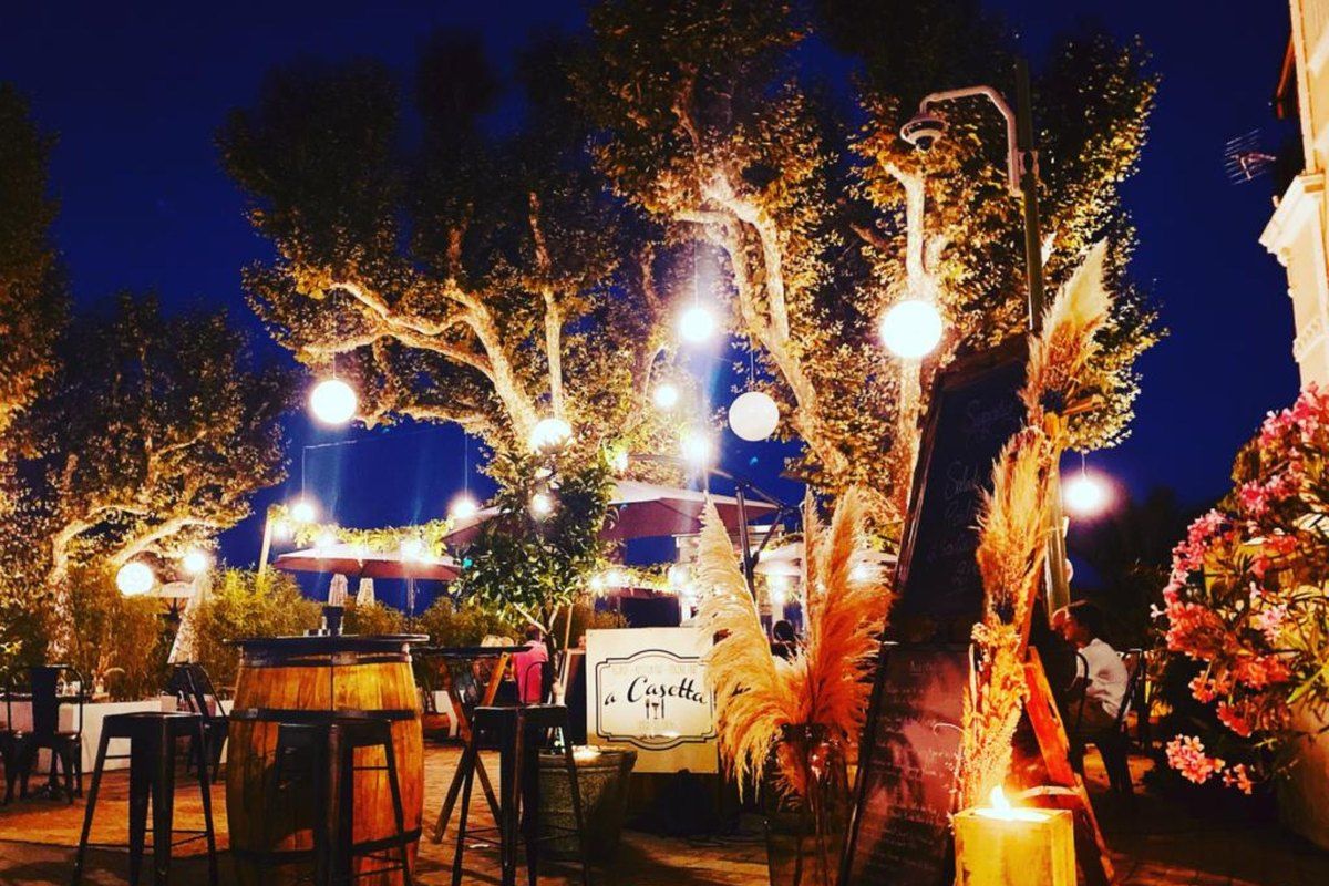 The terrace of A Casetta on Place Bellevue at night, trees strung with lights