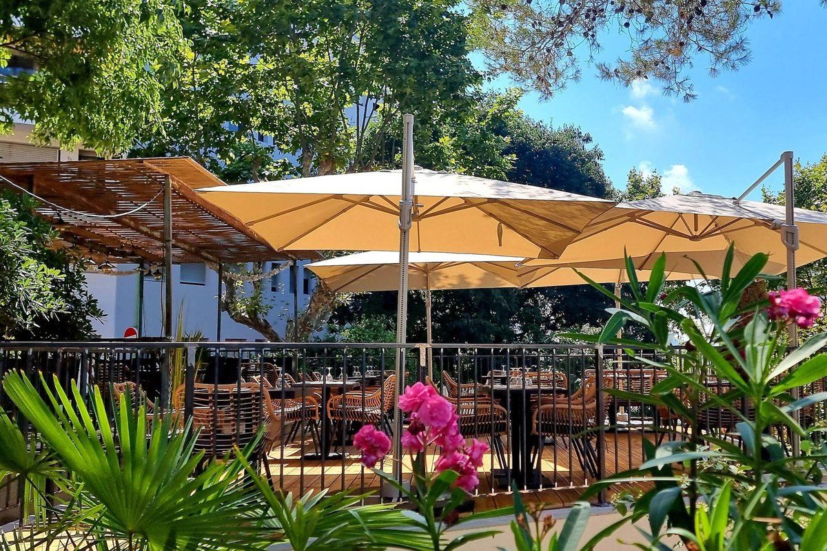 Parasols and greenery on the shaded terrace of Le Bistro du Cannetan