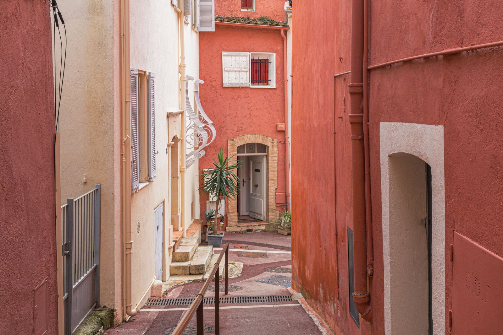 A narrow lane with steps between red and ochre houses in Le Cannet