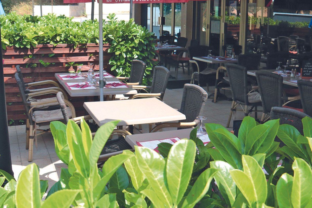 The planted terrace of Le Méditerranée in Le Cannet, laid with tables
