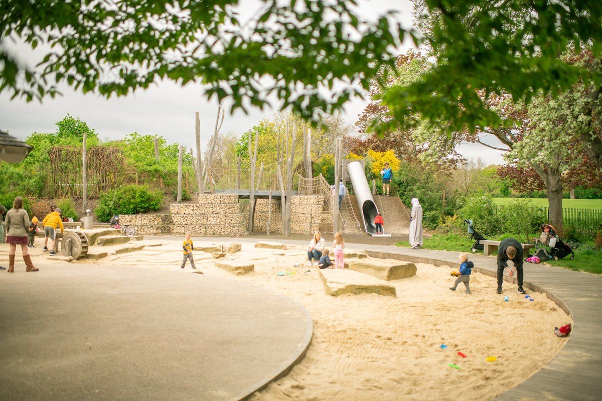 Children playing in the sand around the slide tower at Gloucester Gate Playground in The Regent's Park