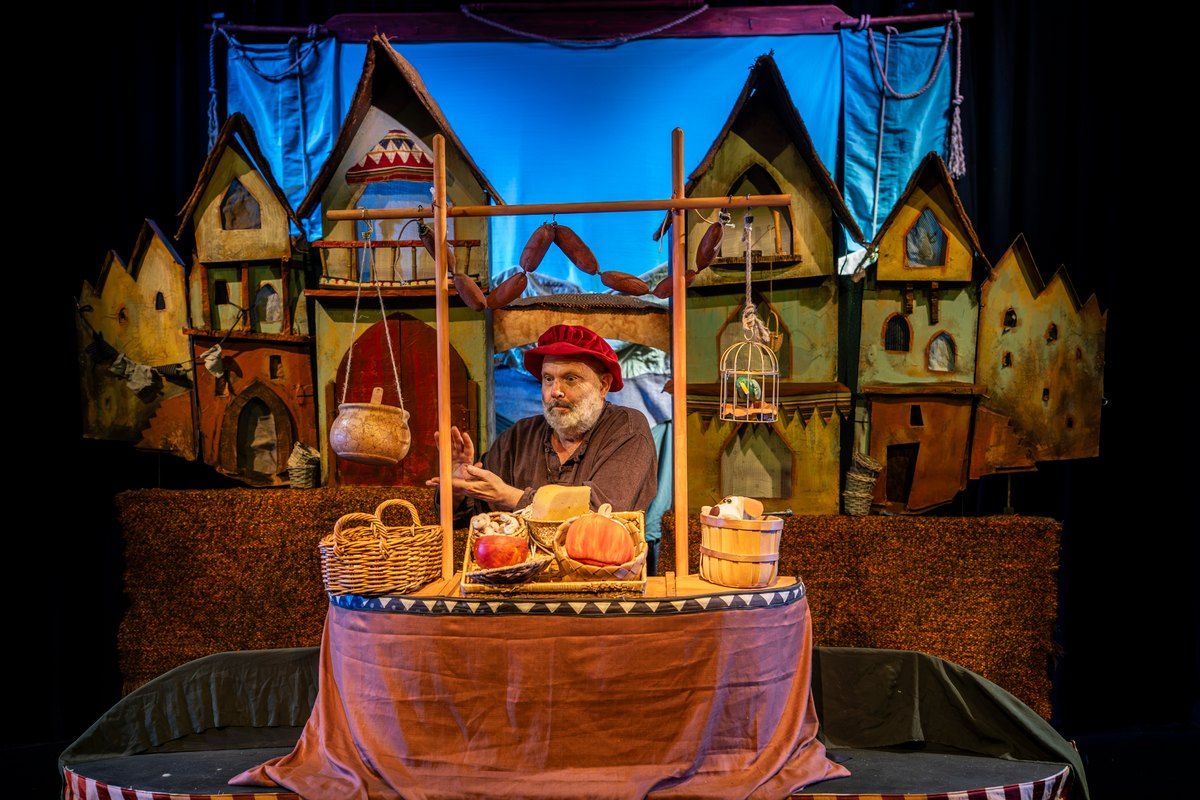 A puppeteer on the stage of Little Angel Theatre in front of a puppet-town set from The Pied Piper