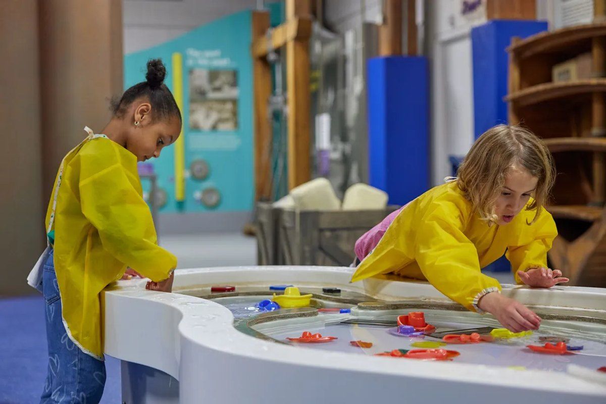 Two children playing at a water table in the Mudlarks family gallery at London Museum Docklands