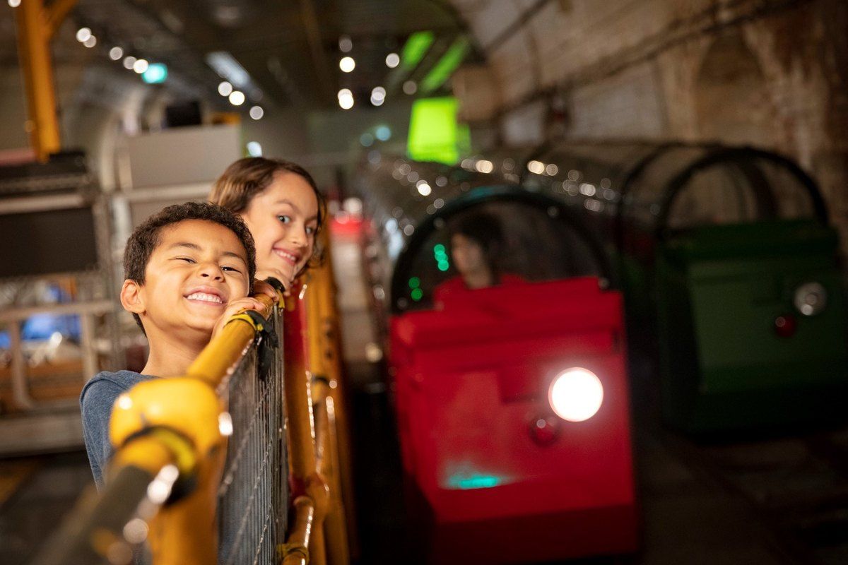 Two children riding the Mail Rail train through the old Post Office tunnels at The Postal Museum