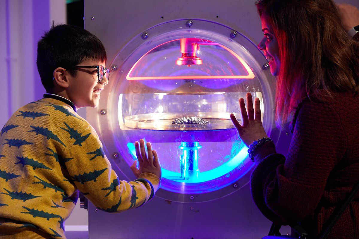 A boy and a woman with their hands on a glowing hands-on exhibit in Wonderlab at the Science Museum